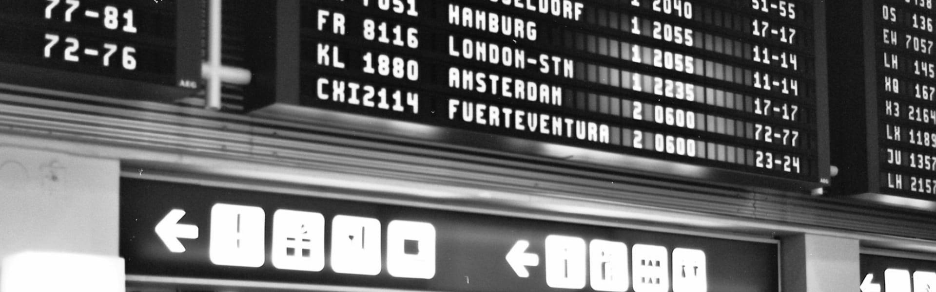 Airport flight information board showing city names and flight numbers.