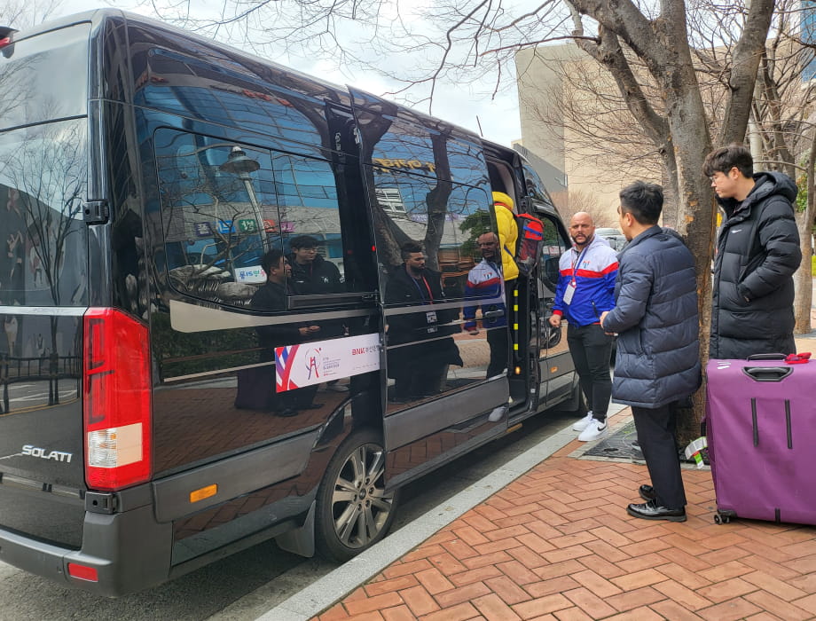 People waiting to board a black van.