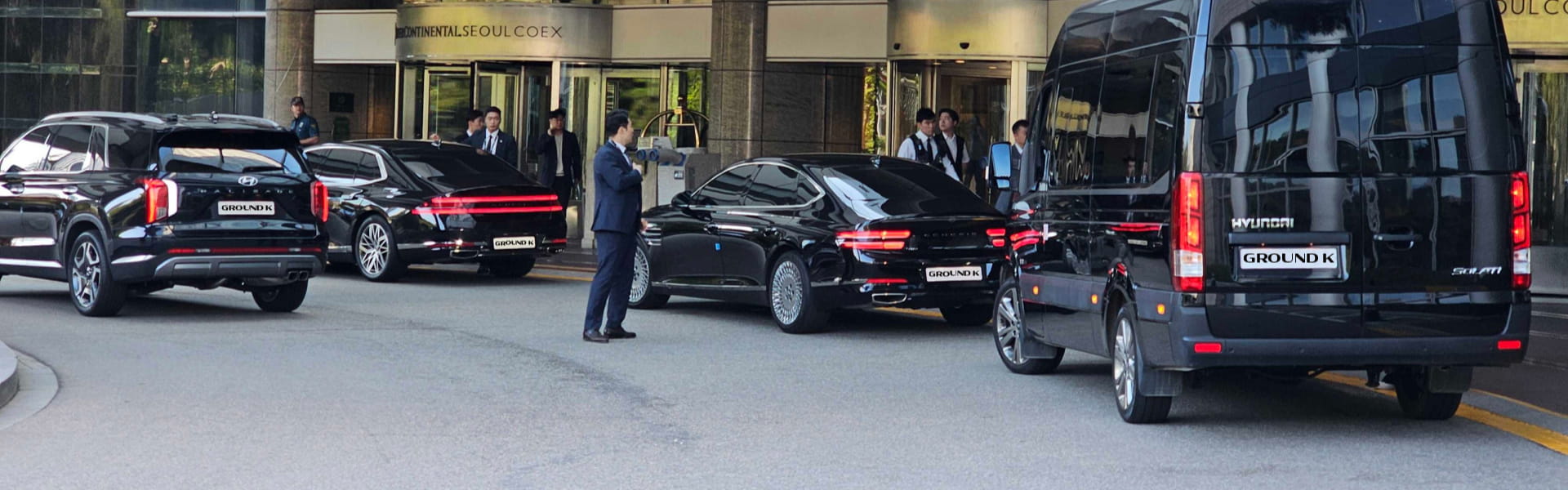 Black protocol vehicles lined up in front of COEX with security personnel and chauffeurs waiting.