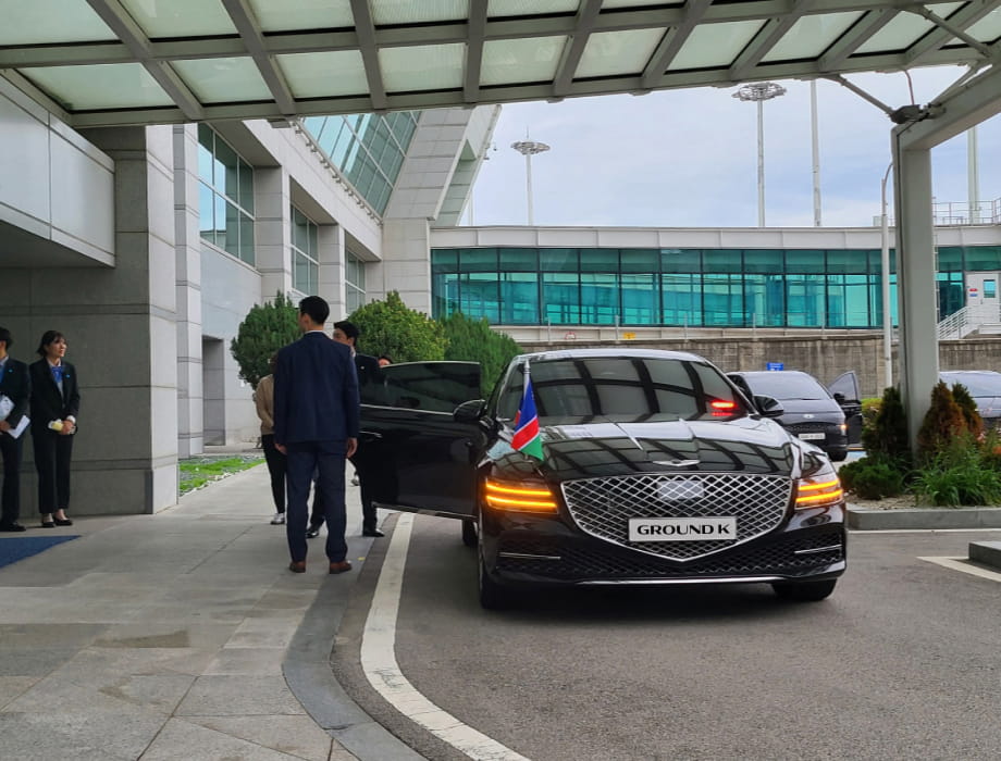 Professional chauffeur holding the door of a black luxury sedan, waiting for a VIP.