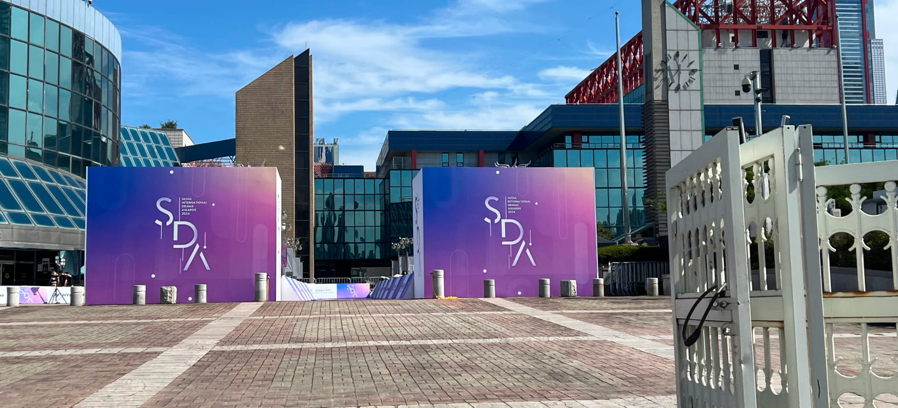 Exterior view of the 2024 Seoul International Drama Awards (SDA) venue entrance featuring large purple branding structures and banners.