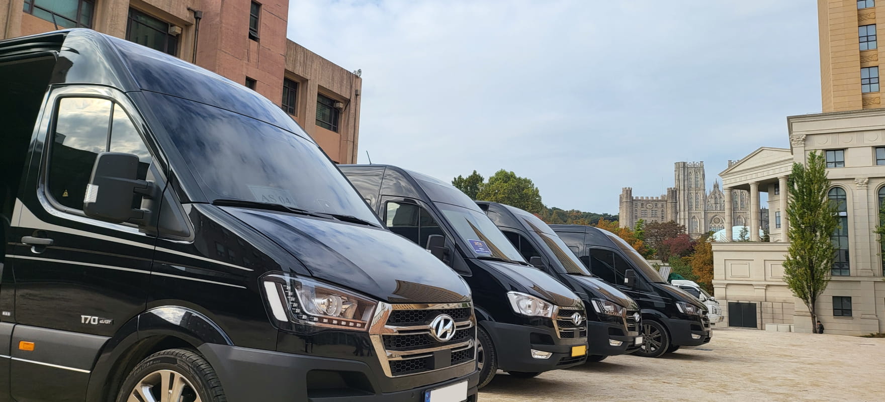 A row of black Hyundai Solati (H350) shuttle vans parked in an outdoor staging area for the AFC 2023 Annual Awards transportation.