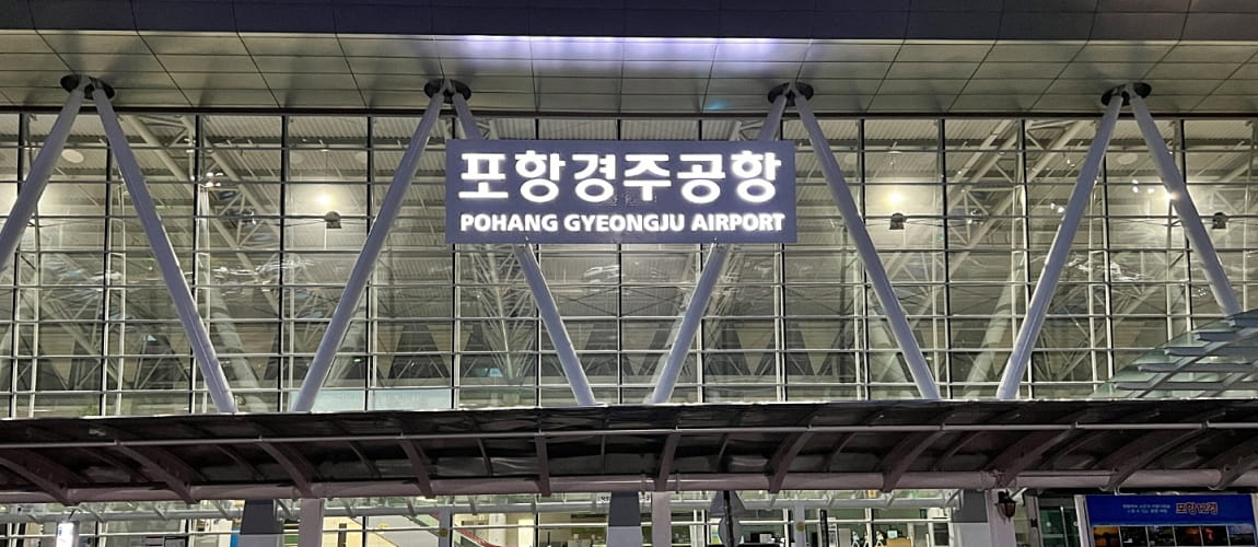 Night view of Pohang Gyeongju Airport terminal in South Korea, with illuminated signage and modern glass architecture.
