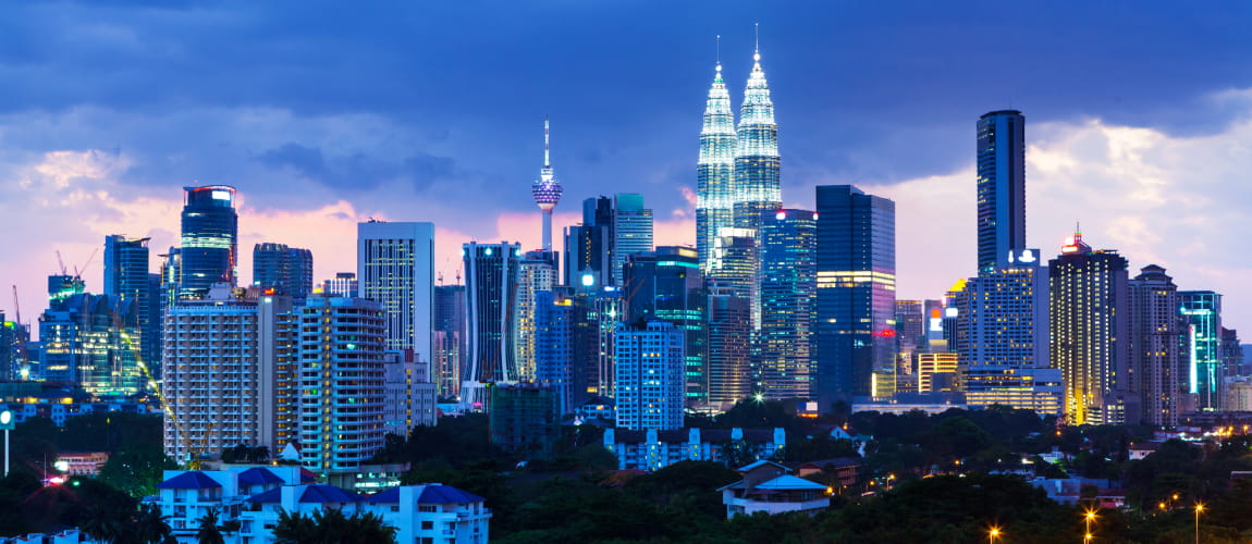 Night view of Kuala Lumpur skyline with Petronas Towers and KL Tower, showcasing the city's vibrant urban landscape.