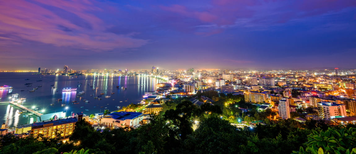 Pattaya’s nightlife by the water, featuring illuminated buildings and boats, perfect for coastal luxury.